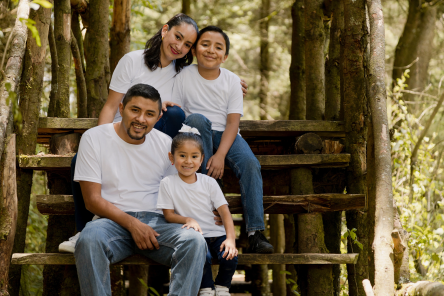 Hispanic family enjoying nature in the park - young parents with their children outdoors smiling at camera