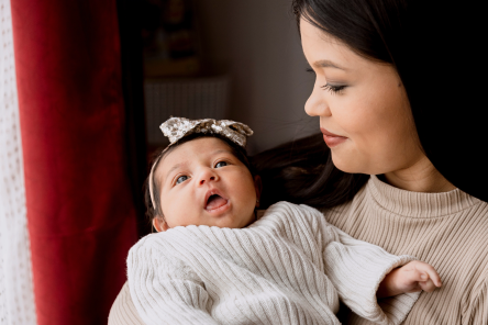 Hispanic mom taking care of her newborn baby of hers while she holds him in the arms of her-latin mother and daughter at home.