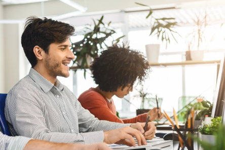 Photo of a man and woman in front of their computers.