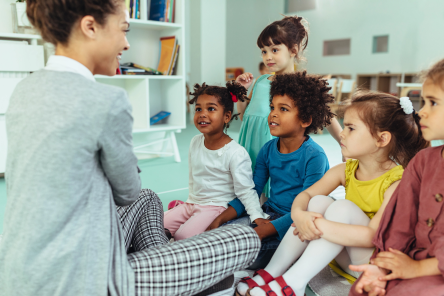 A Meck Pre-K teacher is interacting with a diverse group of engaged, young students.